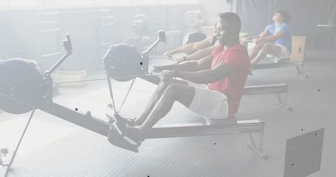 Focused athlete rowing on ergometer in bright gym during indoor cardio training
