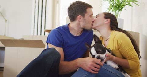 Loving Couple Kissing While Holding French Bulldog