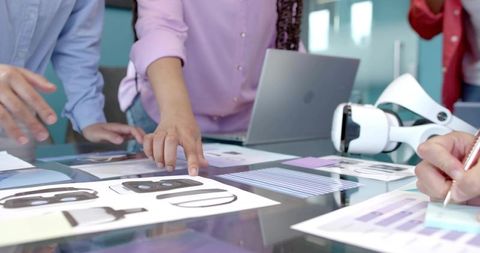 Team collaborating on vr headset design and ux prototyping on glass table in office