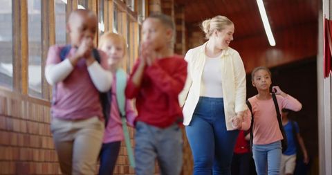 Teacher Guiding Elementary Students in School Corridor