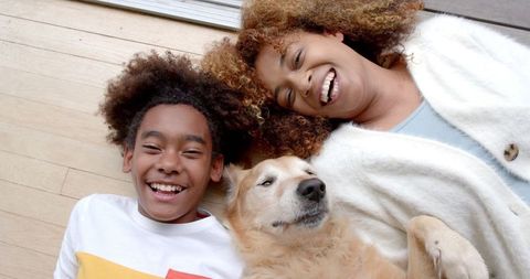 Joyful mother and son bonding with pet dog on floor