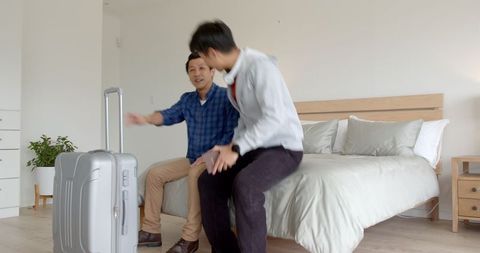 Two Men Packing Suitcase for Vacation in Modern Bedroom