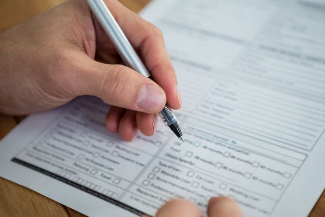 Close-up of a person filling out a last will and testament form with a pen. This image can be used for articles or websites related to estate planning, legal documentation, personal finance, and inheritance. It is suitable for illustrating the process of preparing legal documents and making important financial decisions.