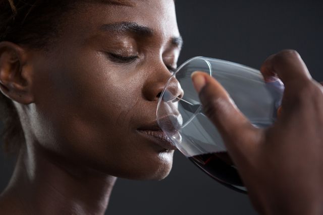 This image captures an androgynous person savoring a glass of red wine, highlighting themes of relaxation and sophistication. Ideal for use in lifestyle blogs, wine tasting promotions, or advertisements focusing on elegance and leisure.