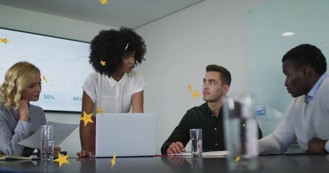 Female leader presenting to team in modern boardroom with laptop and data display