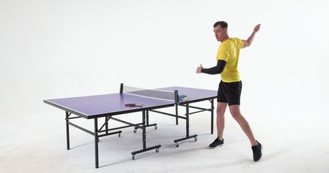 Athlete in Studio Swinging Paddle Next to Tactical Ping Pong Table