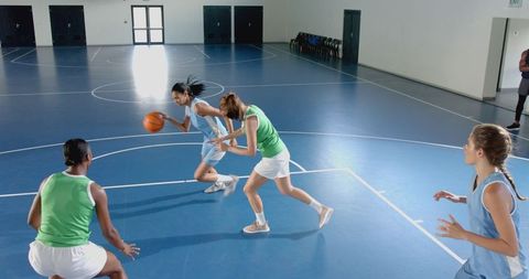 Women practicing basketball in indoor court