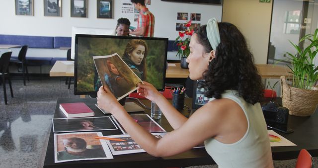 Photograph depicts a creative professional reviewing project materials in a modern office environment. Ideal for use in articles about teamwork, productivity, creative work environments, graphic design, and modern workspaces.