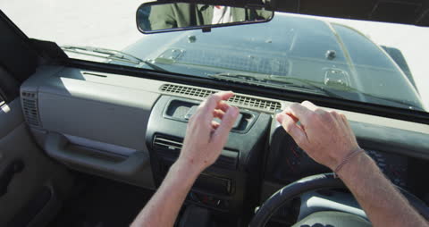 Man Adjusting Rearview Mirror in Car on Sunny Day
