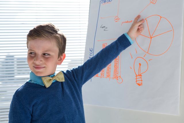 Boy as business executive presenting on white board in office