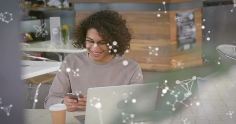 Smiling Man Using Smartphone and Laptop Amidst Molecular Network Overlay in Cafe