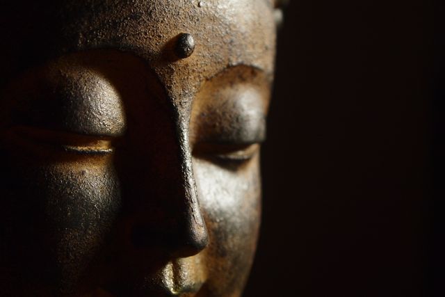 Buddha face in close-up showcasing serene expression with eyes closed and gentle smile. Suitable for use in spiritual, mindfulness, and meditation themes. Ideal for banners, posters, and websites promoting relaxation, inner peace, and holistic wellbeing.