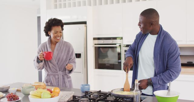 Image of happy african american couple preparing breakfast and coffee together in kitchen. Love, relationship and spending quality time together concept.