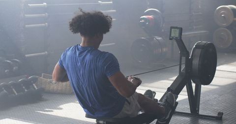 Man Using Rowing Machine in Gym for Intense Workout
