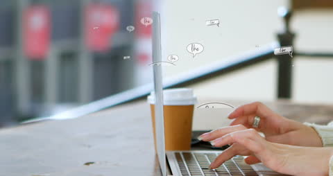 Close-Up of Hands Typing on Laptop with Coffee Cups and Digital Text Overlays