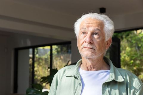 Senior Man Reflecting in Sunlit Modern Room with Tranquil Atmosphere