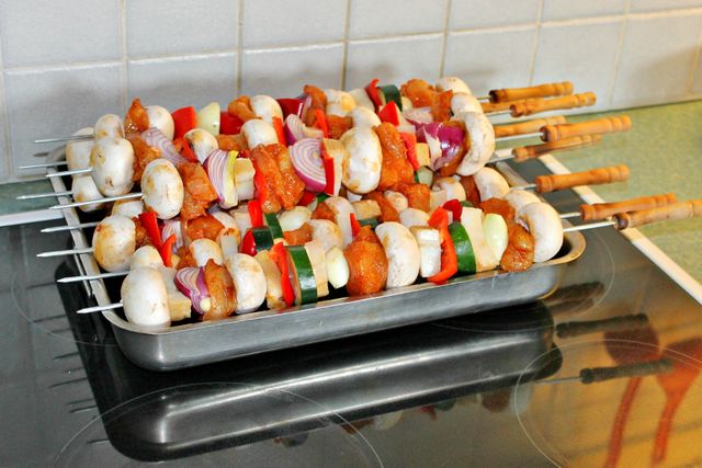 Colorful vegetable and chicken skewers are assembled and ready for grilling, featuring a variety of fresh ingredients including bell peppers, mushrooms, zucchini, and red onions. This cheerful and appetizing arrangement is perfect for illustrating backyard barbecues, healthy eating, and home-cooked meals in a kitchen environment. Ideal for use in cookbooks, food blogs, and advertisements promoting healthy lifestyle choices or grilling equipment.