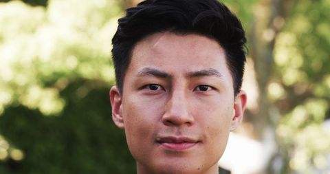 Tranquil portrait of asian man in sunlit park with lush foliage
