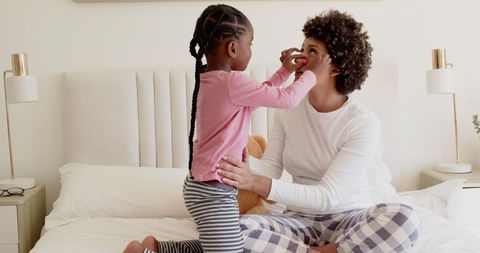 Daughter Playing with Mother in Comfortable Bedroom Scene