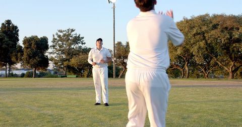 Cricket teammates signaling on outfield during golden hour practice and training