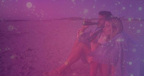 Romantic couple enjoying beach sunset under fringed shawl