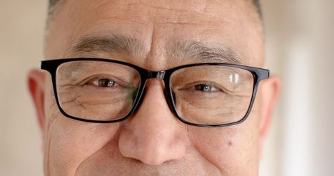 Close-up of elderly man wearing black glasses showcasing facial wrinkles