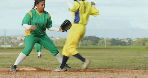 Female softball players during base slide play with fierce competition
