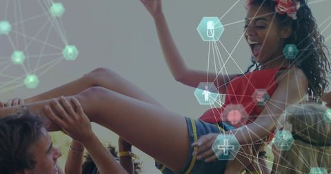 Festival crowd lifting joyful young woman wearing red top and floral headband