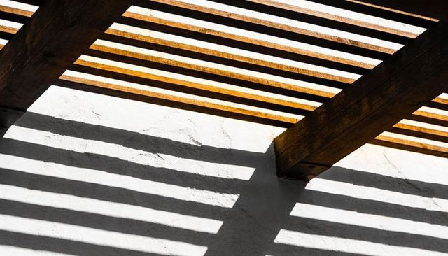 Sunlit Pergola Casting Geometric Striped Shadows on White Stucco Wall, Diagonal Lines