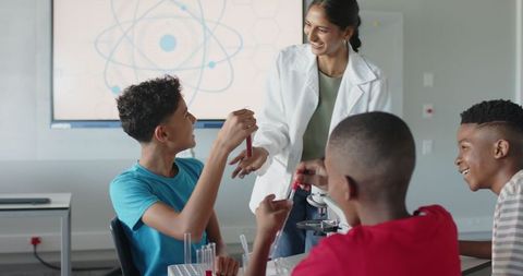 Teacher guiding students in science lab with atomic screen