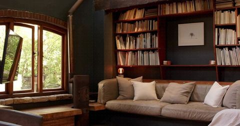 Cozy rustic reading nook with leather sofa, built-in shelves, warm wood tones, ambient lamp