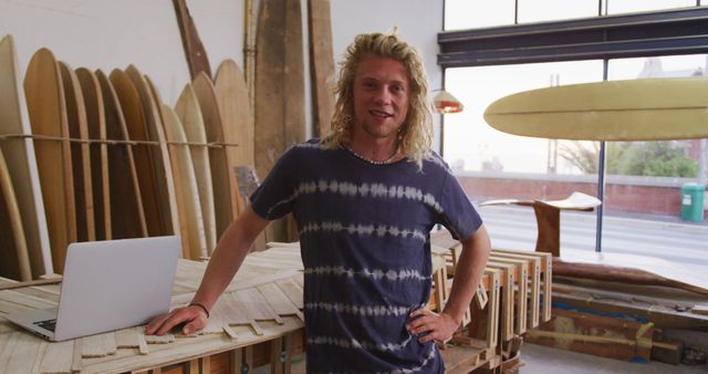 Young surfer standing in surfboard workshop with laptop - Download Free Stock Images Pikwizard.com