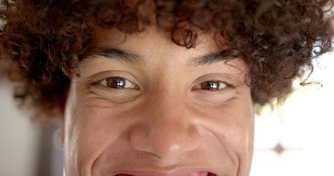 Cheerful Young Man with Curly Hair Showing Friendly Smile