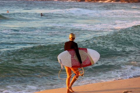 Surfer Holding Board at Golden Hour with Waves