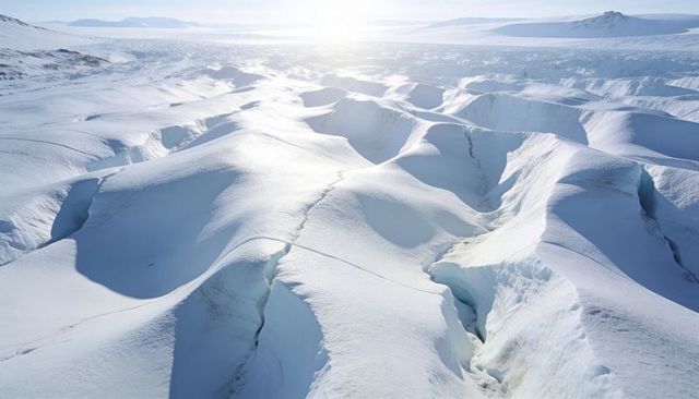Sunlit polar glacier with deep crevasses and wind-sculpted snow ridges, arctic expanse