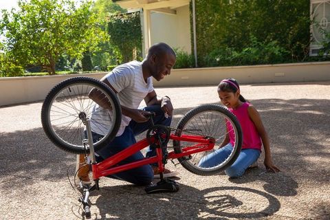 Father and daughter repairing bicycle together outdoors