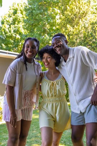 African american friends laughing and embracing in sunlit backyard summer gathering