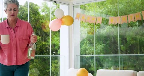 Senior Woman Tidying Living Room After Festive Birthday Celebration