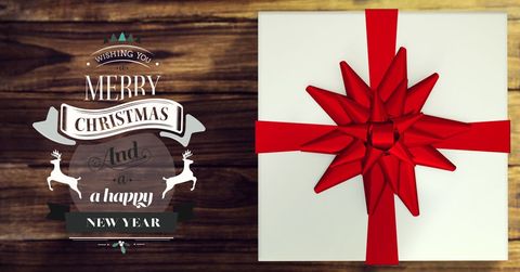 Christmas gift box with red ribbon on wooden table