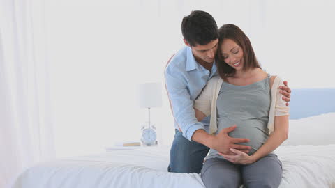 Joyful Expectant Parents Embracing Parenthood on Bed