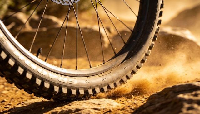 Mountain bike wheel kicking up dust on rocky trail close-up action with knobby tire