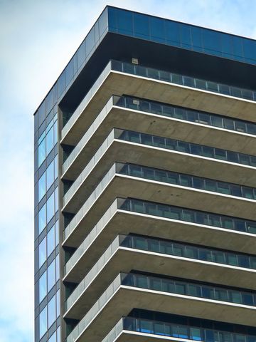 Modern high-rise condo building with glass facade against blue sky