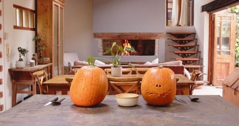 Carved Pumpkins on Table by Cozy Fireplace in Rustic Home