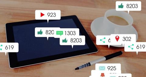 Tablet with social media notifications on wooden desk with coffee and pen