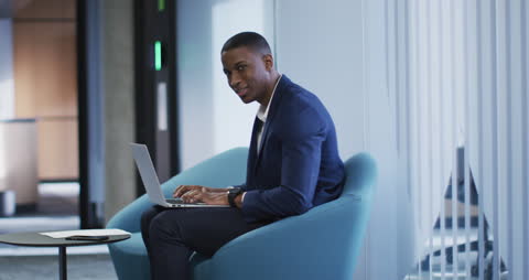 Businessman Working on Laptop in Modern Office Corridor