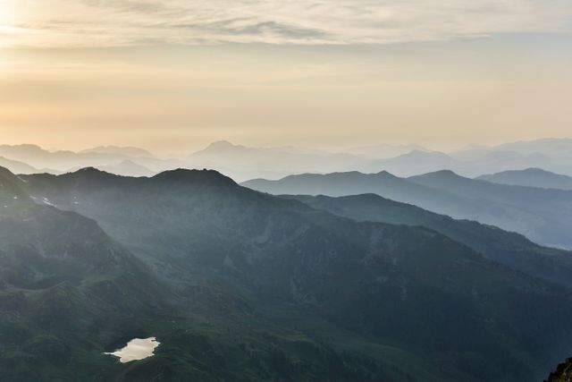 Serene Mountain Range at Sunrise with Hazey Sky and Rolling Peaks - Download Free Stock Photos Pikwizard.com
