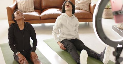 Partner stretching at home with african american woman and man on yoga mats