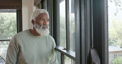 Senior Man Reflecting by Window in Cozy Home Environment