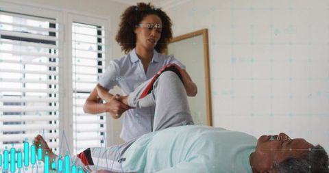 Home physical therapist assisting man with guided leg stretch on treatment bed for rehab