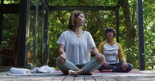 Asian mother and daughter practicing yoga outdoors in garden. at home in isolation during quarantine lockdown.